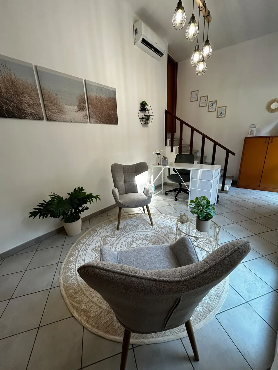 Angolo relax dello studio con poltrone e tappeto, luce naturale e piante